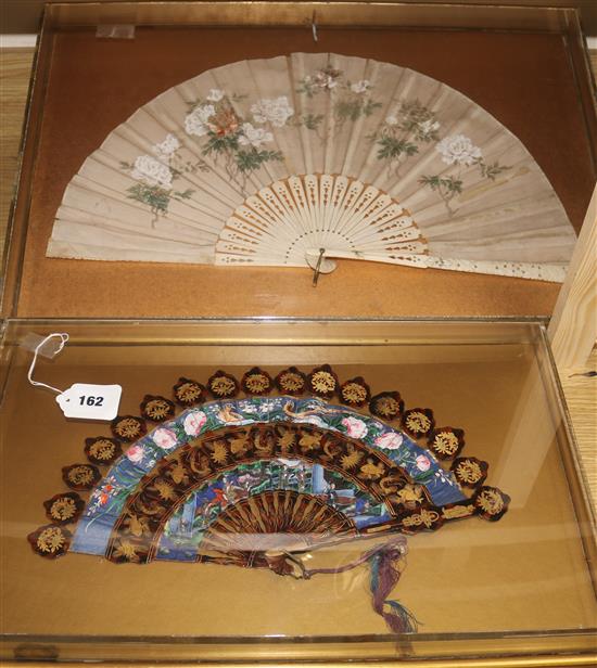 Two Chinese export fans, 19th century, the first a gilt decorated lacquer cabriolet fan, c.1860, length 30cm, both in perspex cases